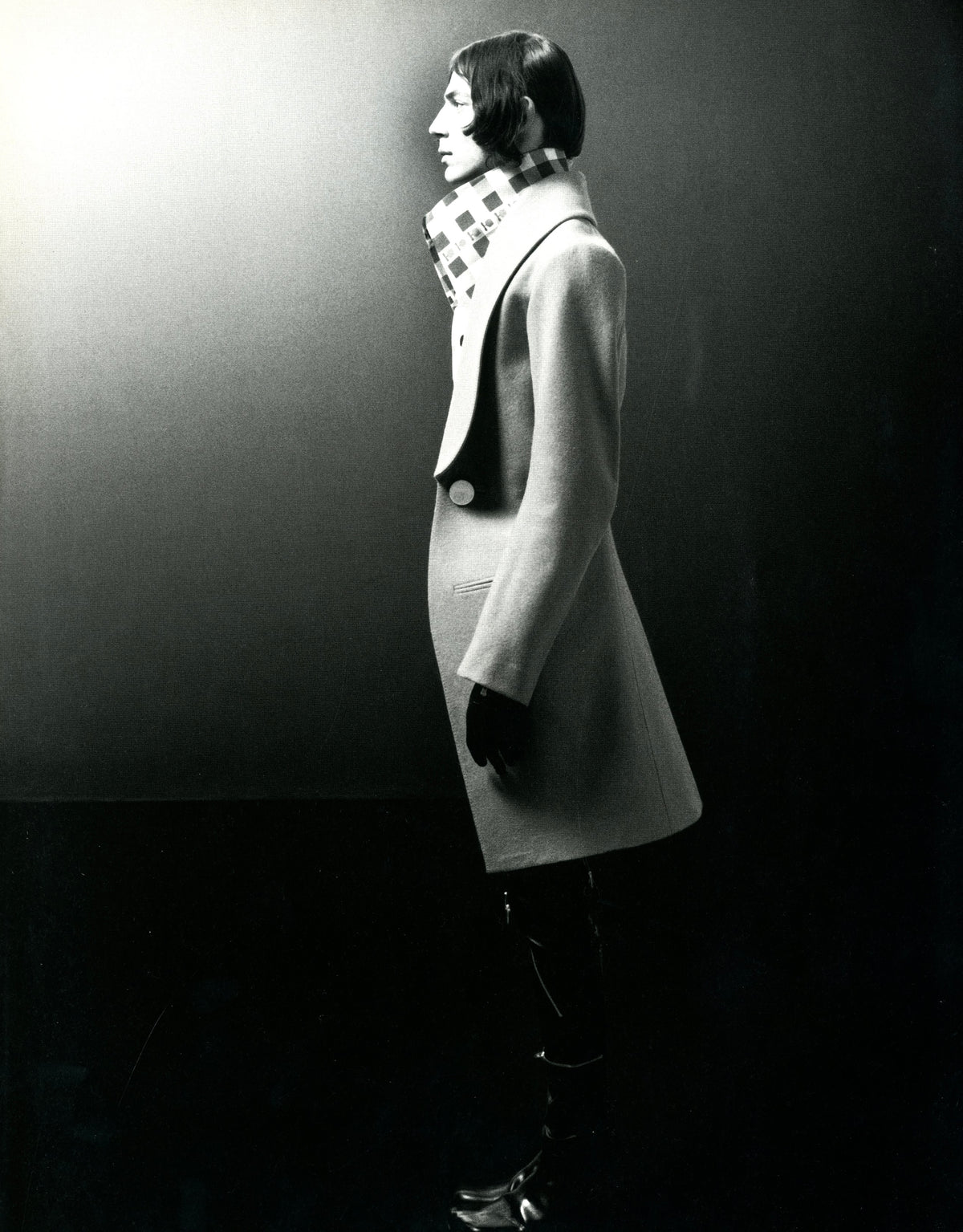 Fashion photograph from A Magazine N°A: figure in profile wearing a long coat with a high standing collar.