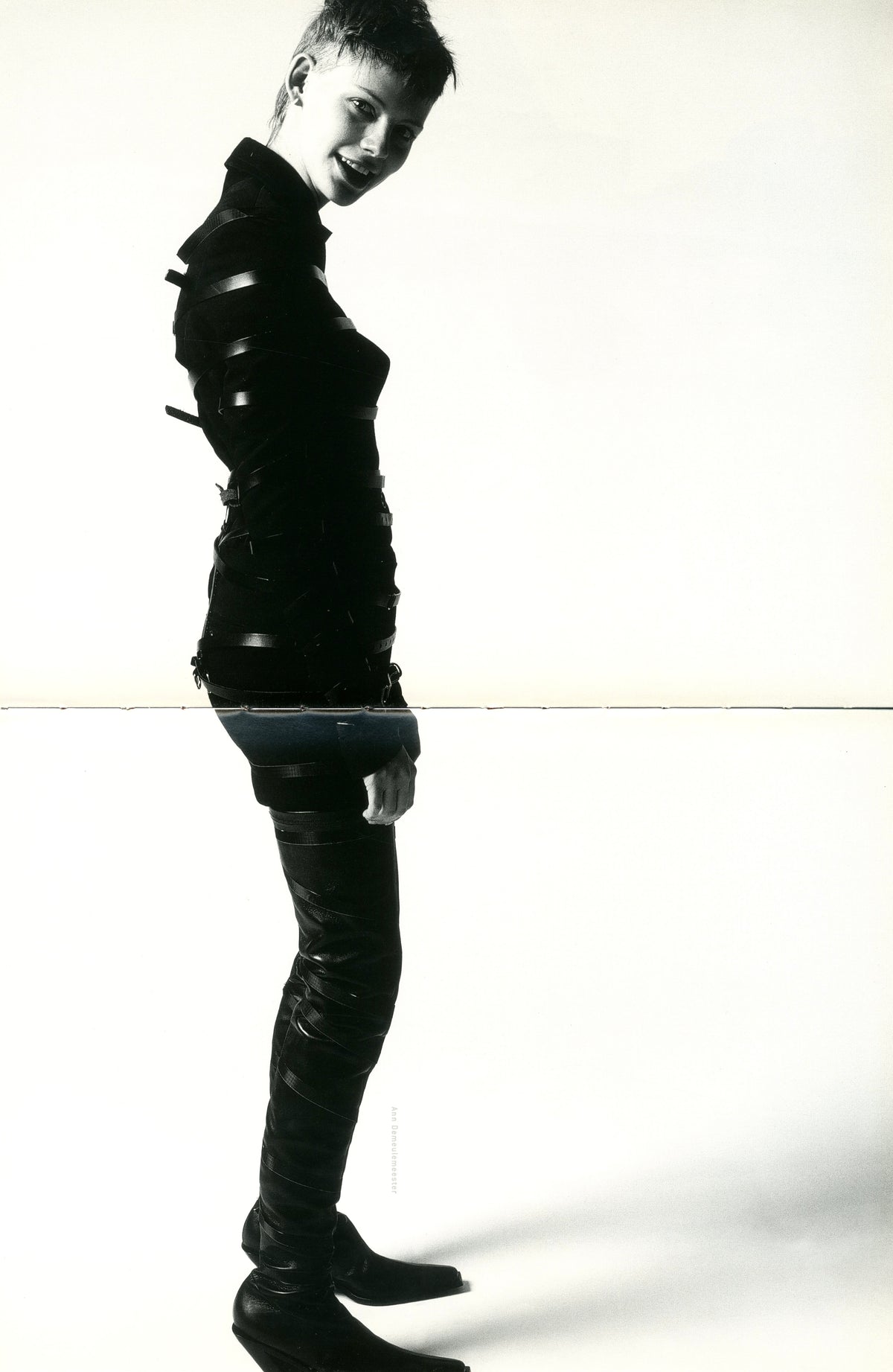 Black-and-white photograph from A Magazine N°A: model in a glossy black outfit standing in profile.