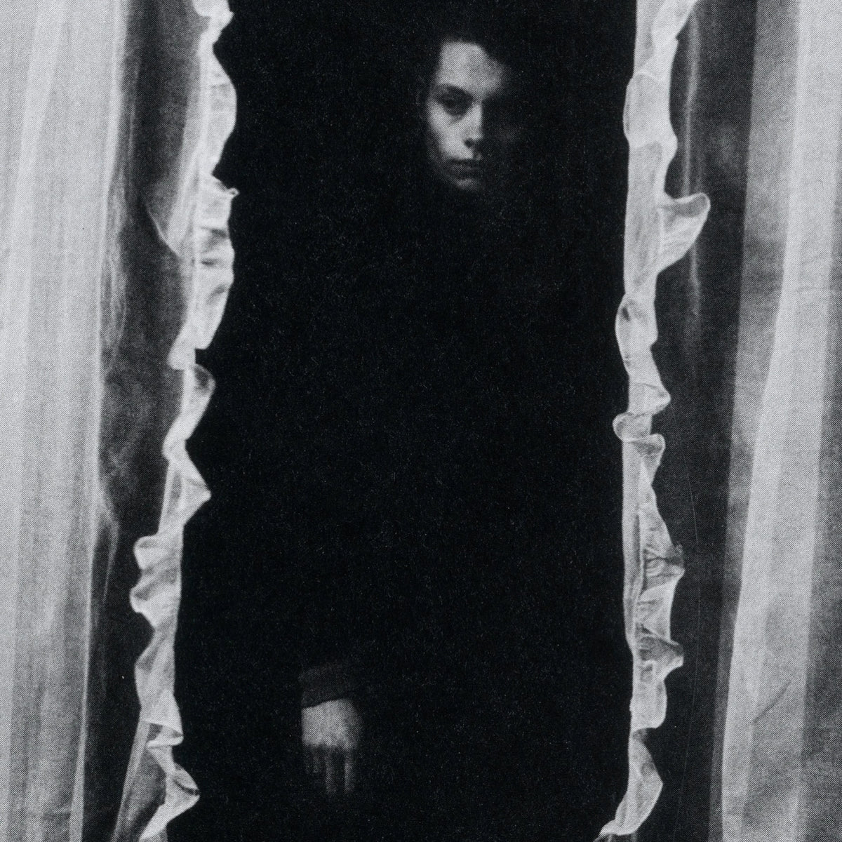 Black and white photograph of a person standing in a dark doorway.
