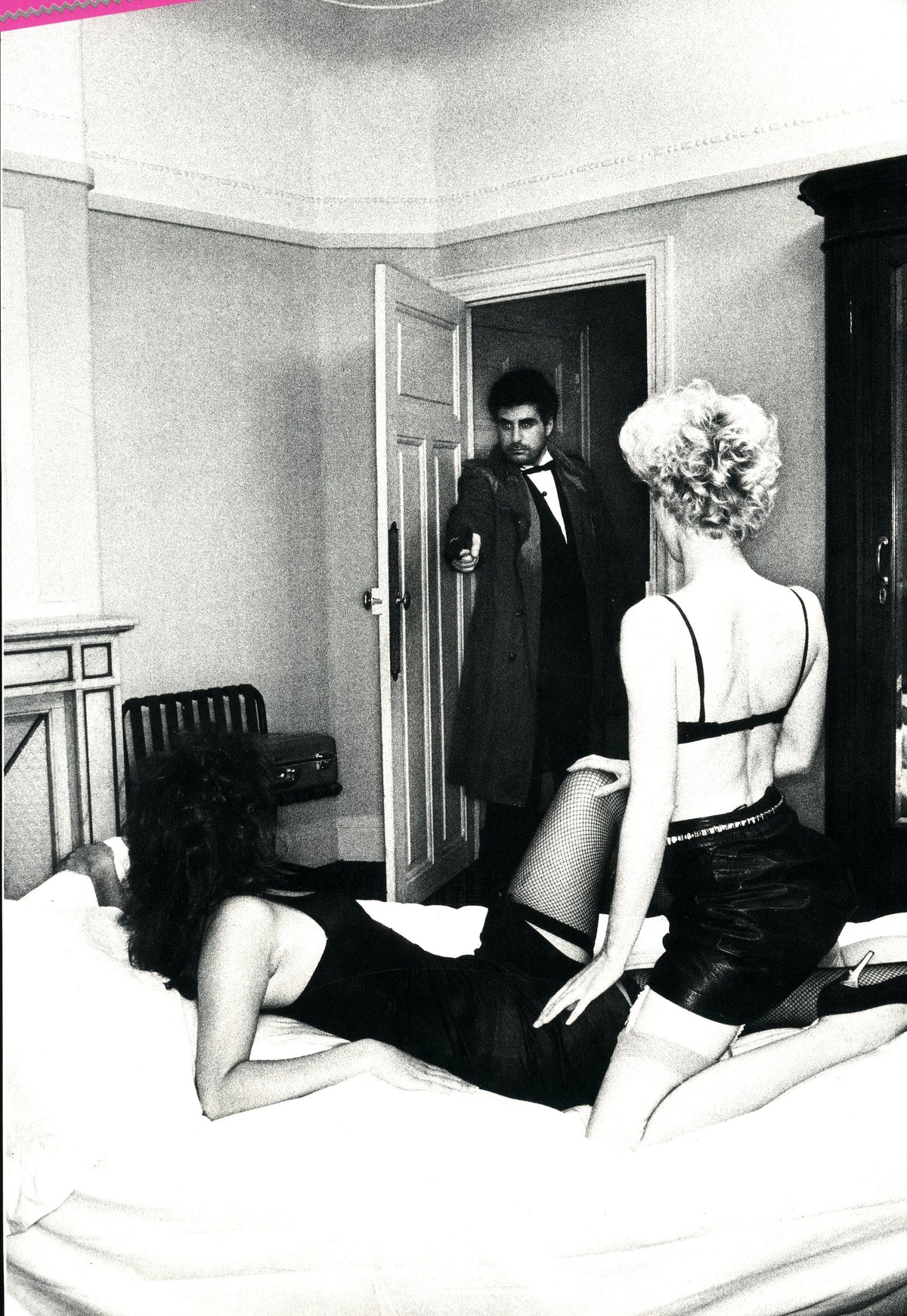 Woman in black lingerie on a bed as a man in a suit stands at the door, black-and-white image from Drunter & Drüber.