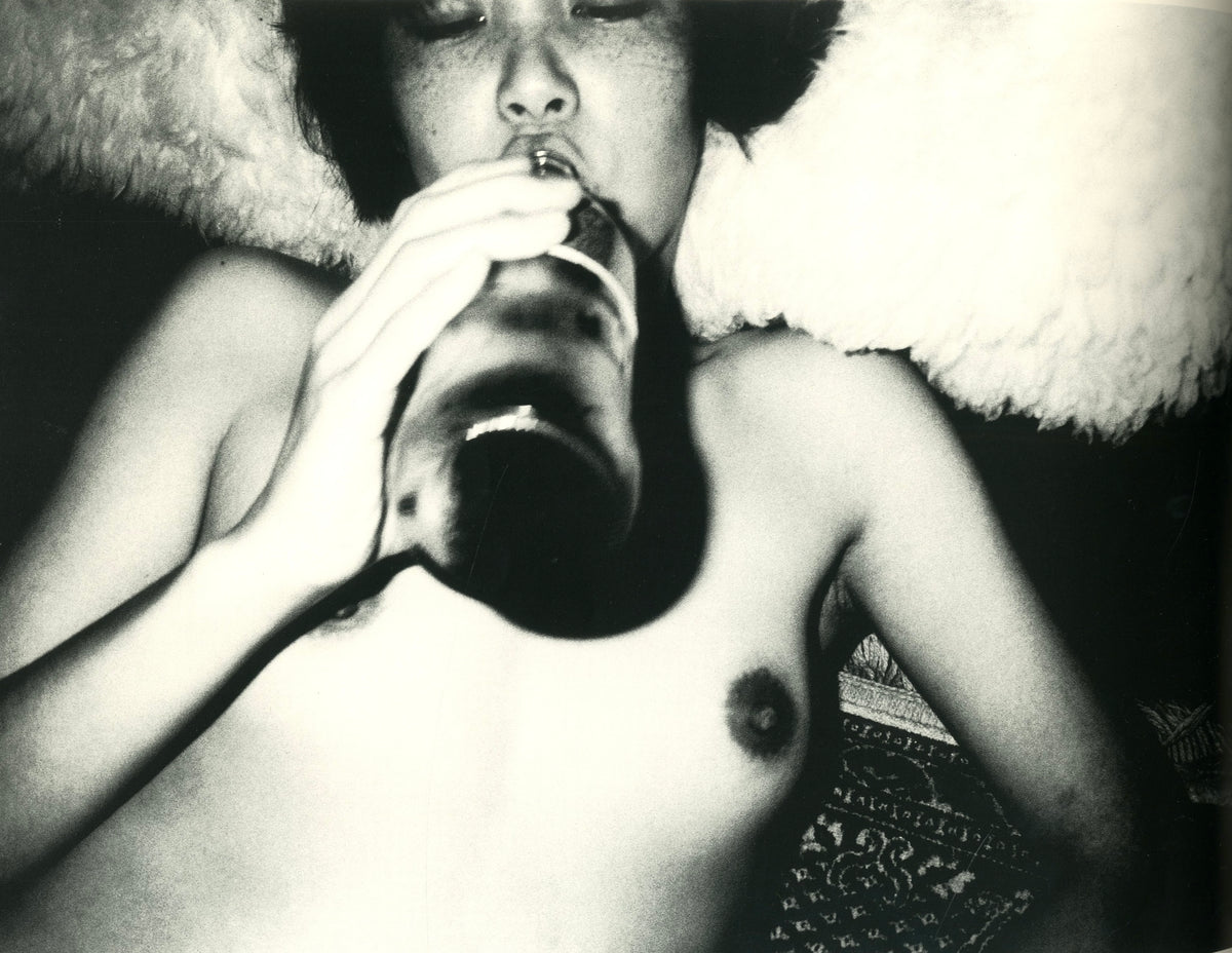 Photograph from Hysteric No. 5: a nude young woman drinking from a bottle, head tilted back, shot from below.