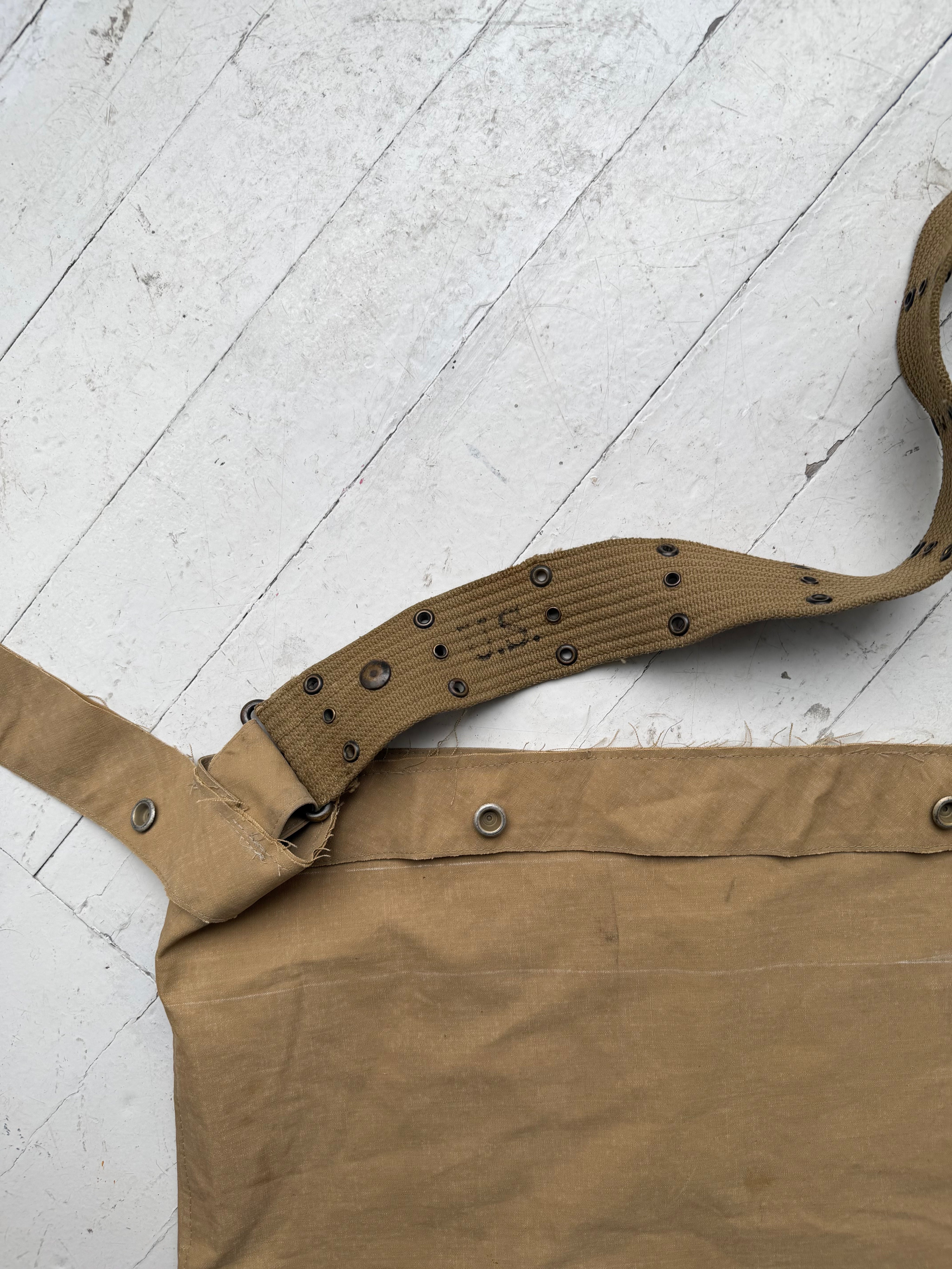 Detail of the olive M1936 web belt with eyelets and metal snaps fastened along the top of the canvas tote.