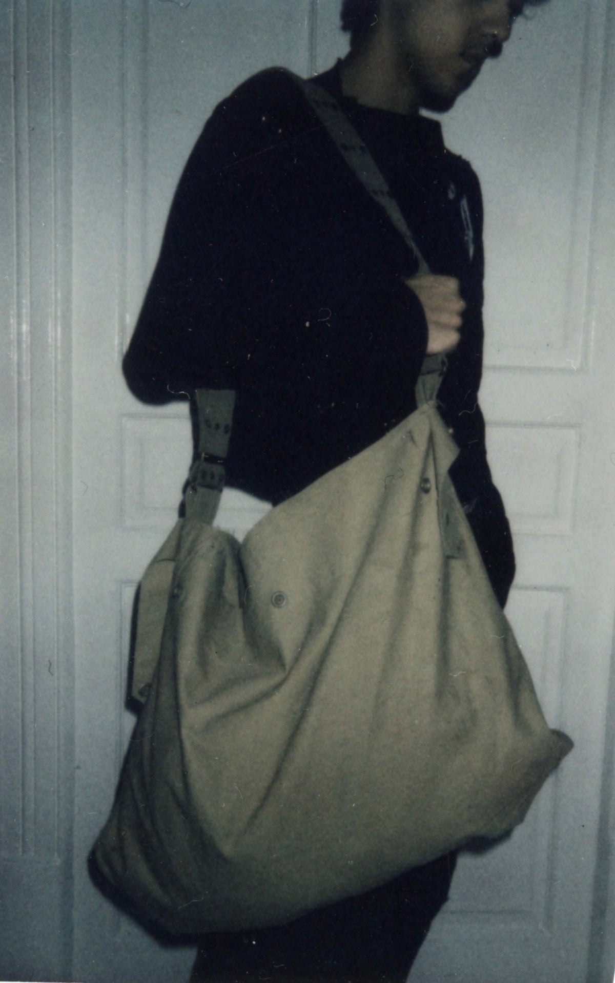 Oversized khaki canvas tote with olive WWII webbing strap, carried on the shoulder.