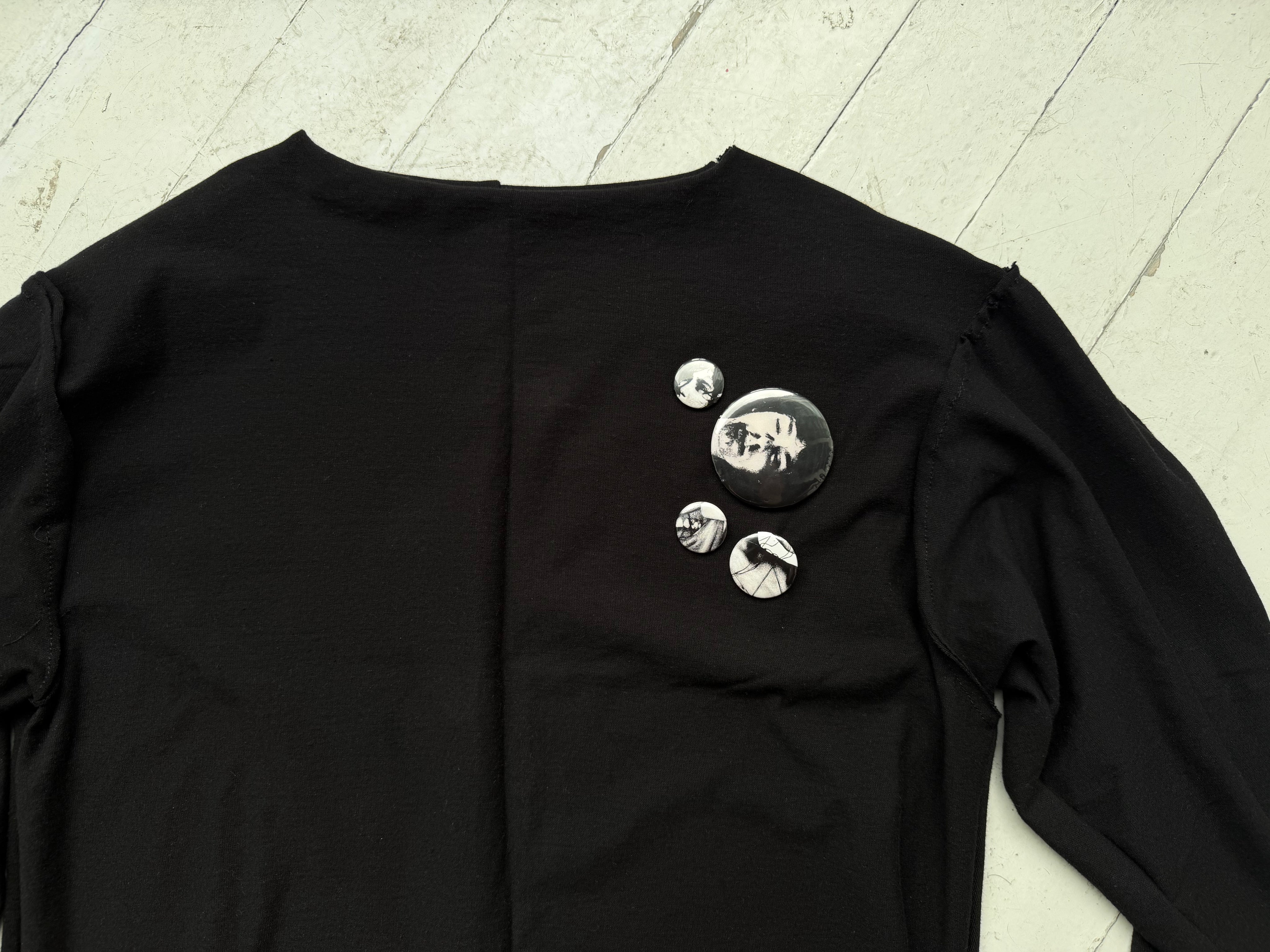 Close-up of three hand-sewn pin-back buttons on the chest of the intermission black top.