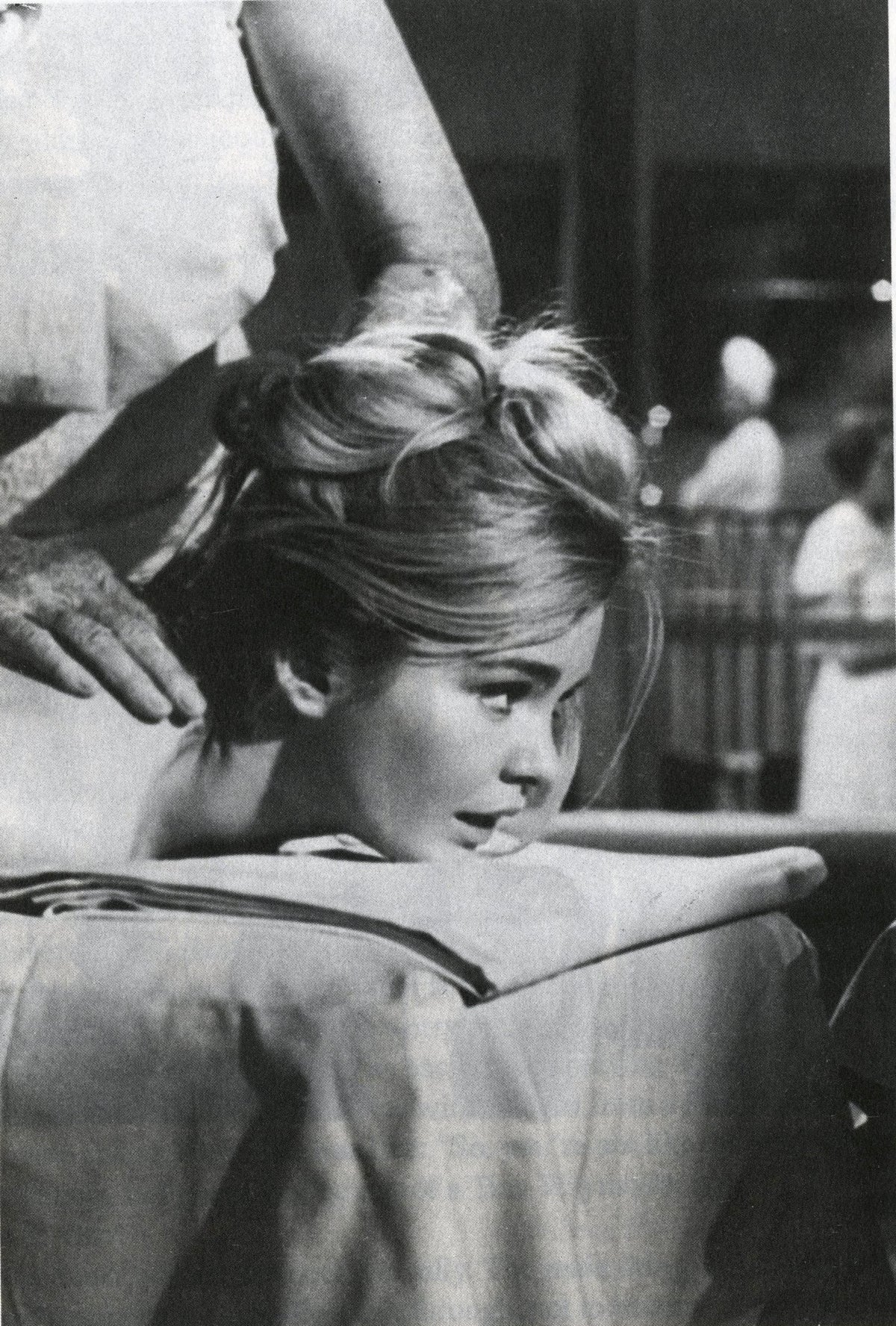 Young woman with her head lowered over a bed, hands in her hair, black-and-white image from Fama & Fortune Heft 8.