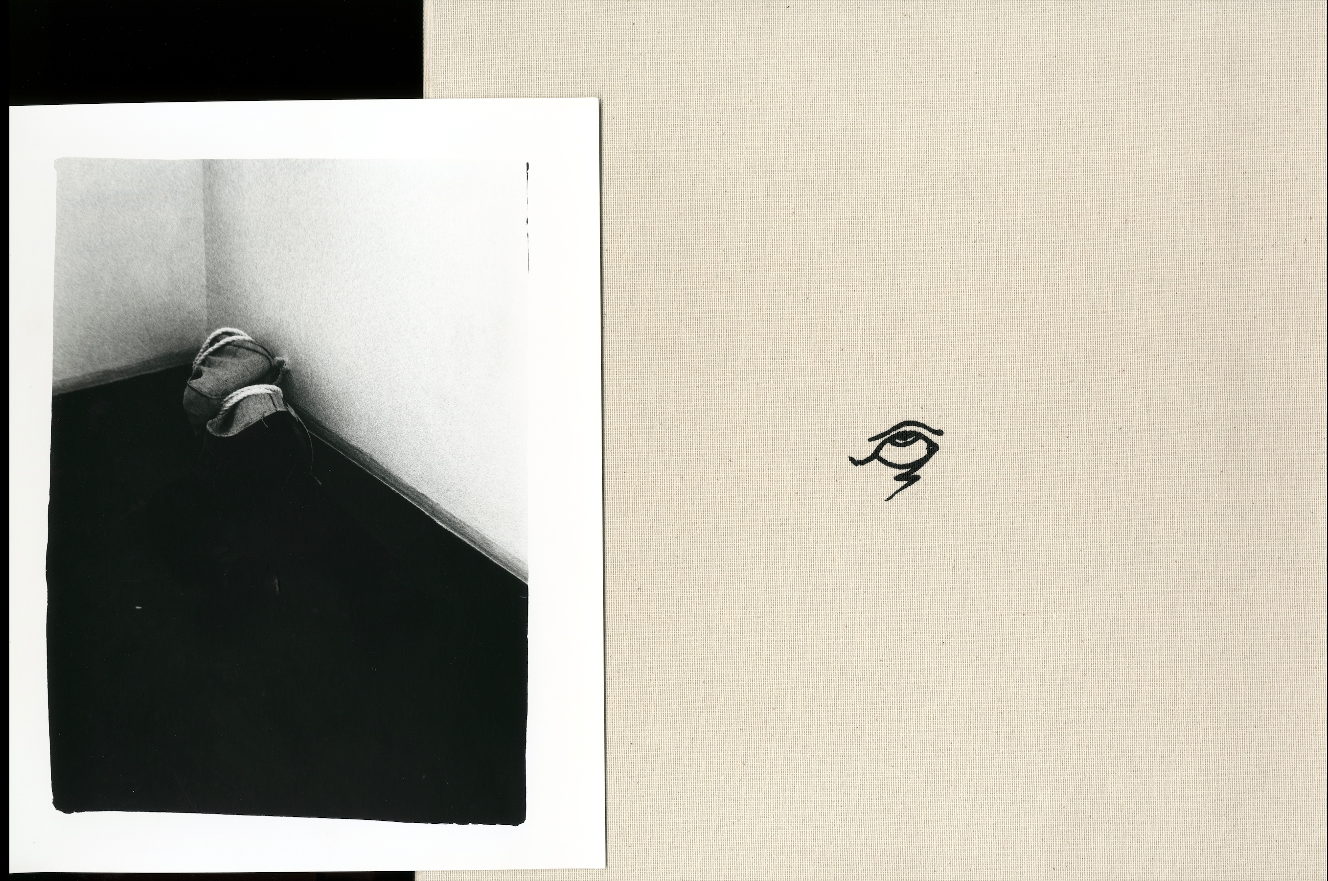 Black-and-white photograph of a figure curled in the corner of a room from the artist book Guiones.