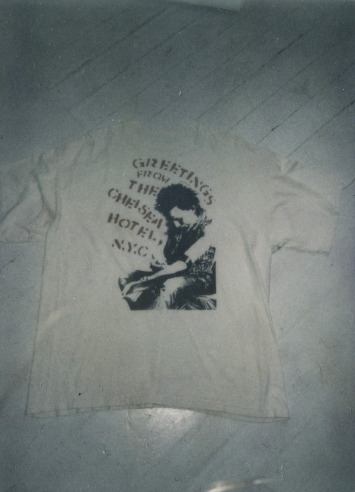 Vintage white T-shirt printed “Greetings from the Chelsea Hotel N.Y.C.” around an image of Sid Vicious, laid flat.