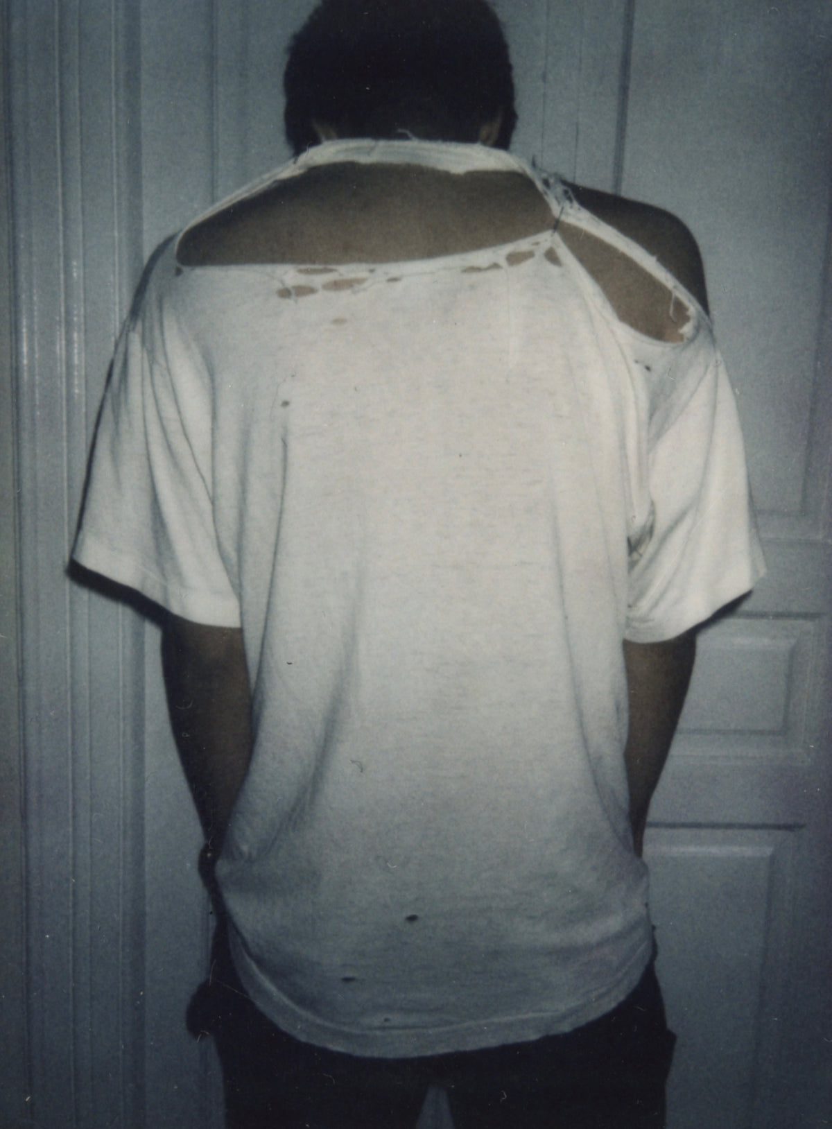 Back of the vintage Sonic Youth T-shirt worn, showing a large tear across the upper back and shoulder.